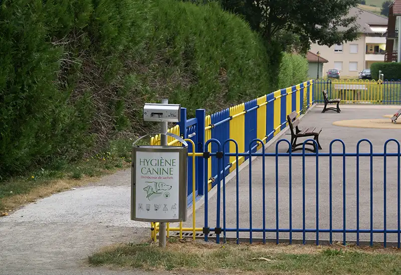 Duo distributeur canin et poubelle de rue avec affichage Distributeur canin en rouleau et poubelle de rue avec couvercle et affichage personnalisé près d'un parc.