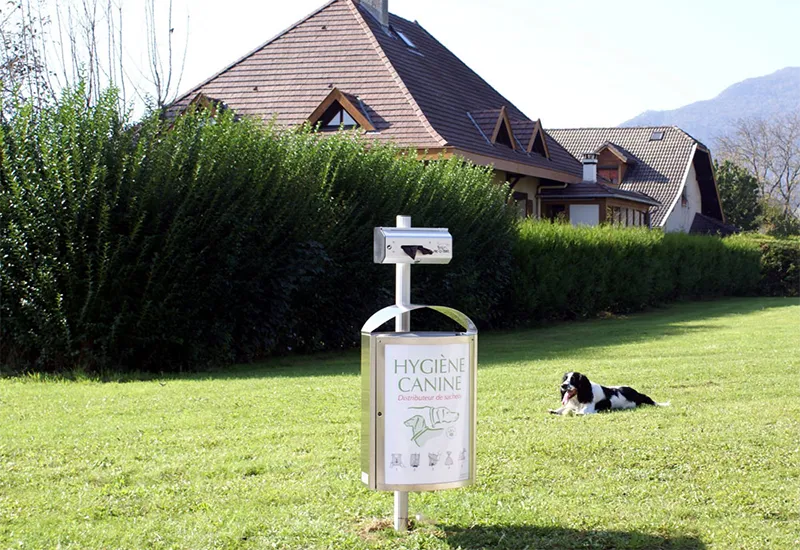 Duo distributeur canin en rouleau et poubelle de rue Distributeur canin en rouleau avec poubelle de rue et affichage sur mât dans un parc.