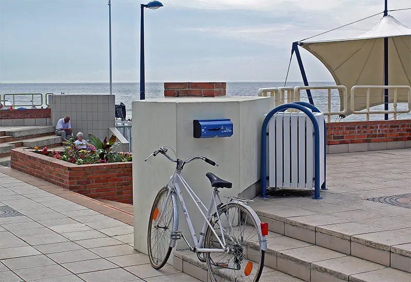 Distributeur canin Aprico Distributeur canin bleu sur un muret dans un environnement près de la mer