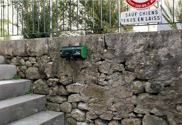 Distributeur canin en rouleau vert Distributeur canin en rouleau sur un muret.